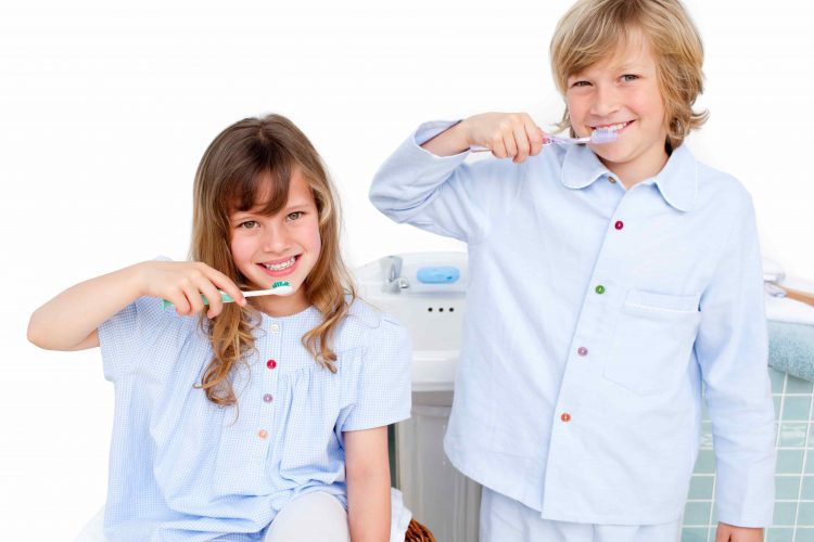 Crianças sorrindo enquanto escovam os dentes - Orthoclin