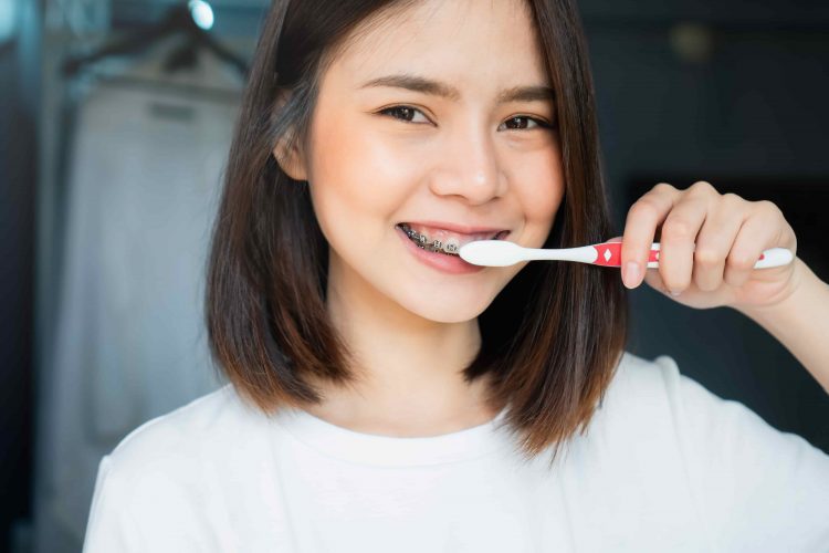Mulher sorrindo enquanto escova os dentes - Orthoclin
