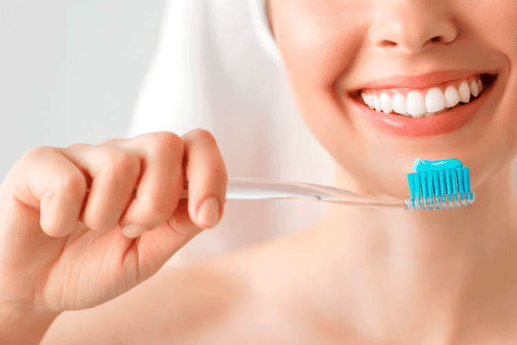 Mulher escovando os dentes durante o tratamento ortodôntico para evitar gengivite, com foco na boa higiene bucal.