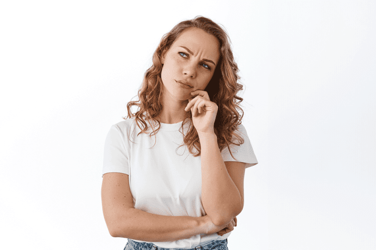 Mulher pensativa considerando o valor dos alinhadores transparentes como opção de tratamento ortodôntico. É importante avaliar as condições específicas do seu caso antes de tomar uma decisão.