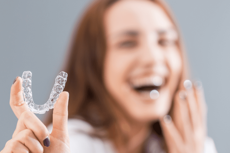 Mulher segurando alinhadores transparentes, destacando como os dentistas estão adotando essa tecnologia inovadora.
