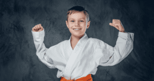 Menino em uniforme de artes marciais mostrando confiança, simbolizando o impacto do sono no desempenho do jovem atleta.