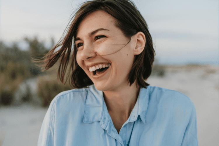 Mulher sorrindo ao ar livre, ilustrando como o valor do sorriso impacta positivamente a saúde emocional e física.
