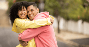 Casal abraçado e sorrindo, destacando o valor do sorriso na construção de relacionamentos saudáveis.