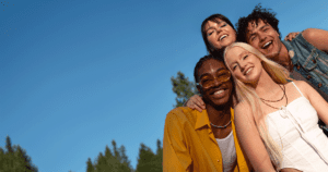 Grupo de amigos sorrindo juntos ao ar livre, simbolizando como o sorriso fortalece laços sociais e inspira felicidade.