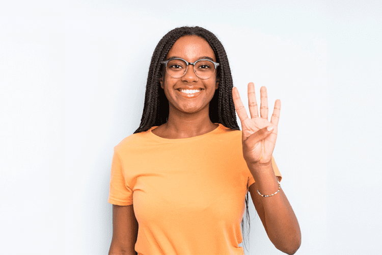 Mulher sorrindo e mostrando quatro dedos, representando os quatro sinais principais para iniciar um tratamento ortodôntico.