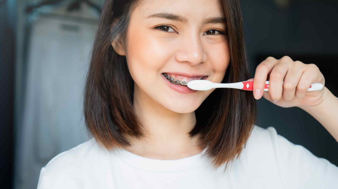Mulher sorrindo enquanto escova os dentes - Orthoclin