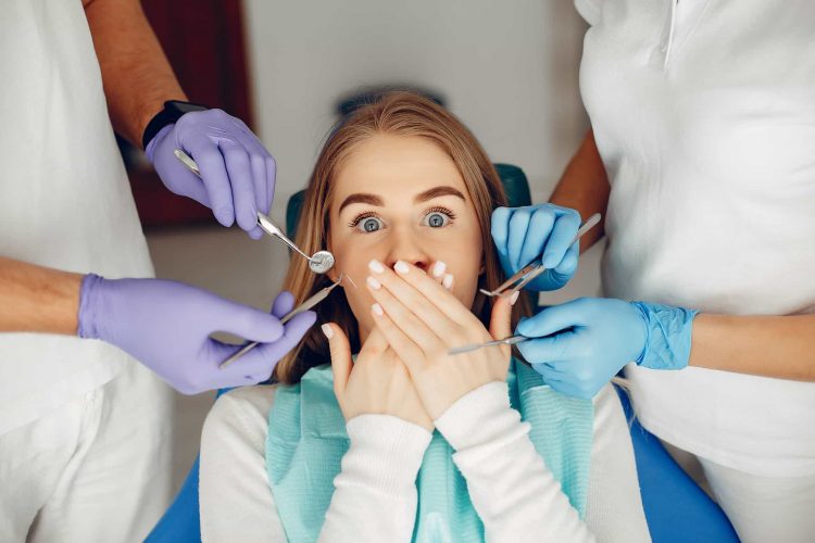 Menina com medo de fazer tratamento ortodôntico sentda numa cadeira de dentista