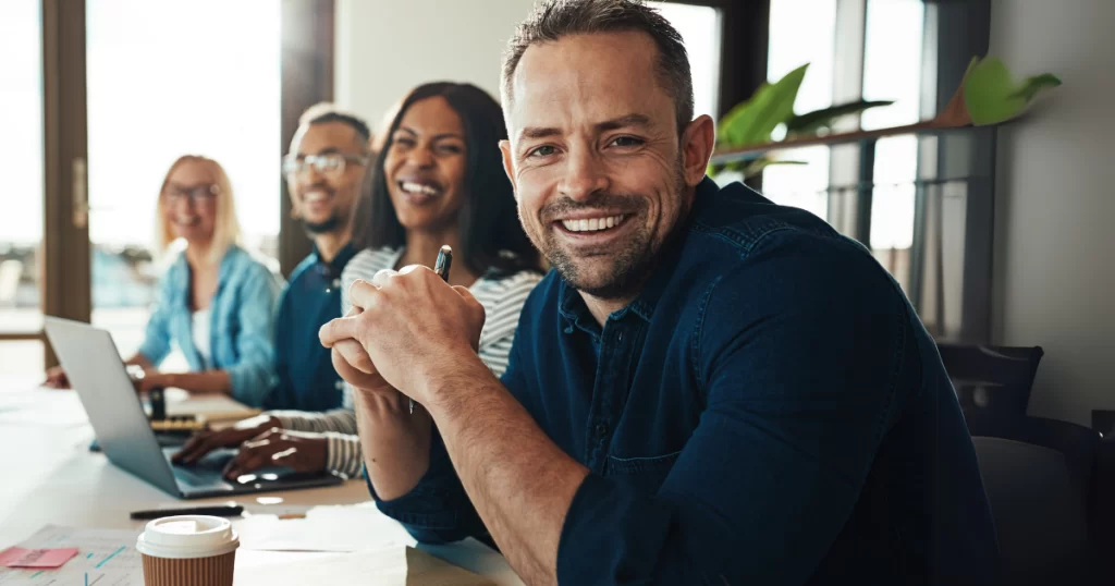Profissionais sorrindo em ambiente de trabalho, destacando a importância do sorriso no trabalho para criar boas relações e transmitir confiança.