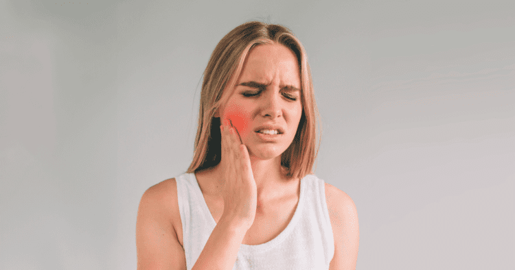 Mulher sentindo dor na região da mandíbula, um sintoma comum de Disfunção Temporomandibular (DTM), que pode fazer tratamento ortodôntico estética