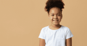 Menina sorrindo, representando o impacto positivo dos aparelhos ortodônticos usados na infância.