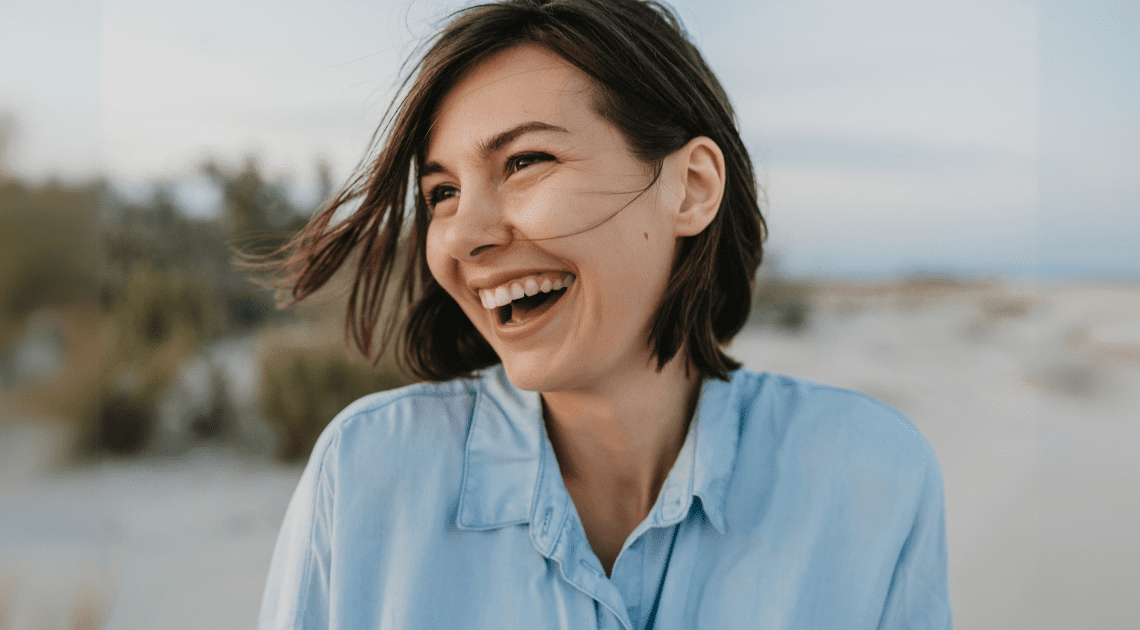 Mulher sorrindo ao ar livre, ilustrando como o valor do sorriso impacta positivamente a saúde emocional e física.